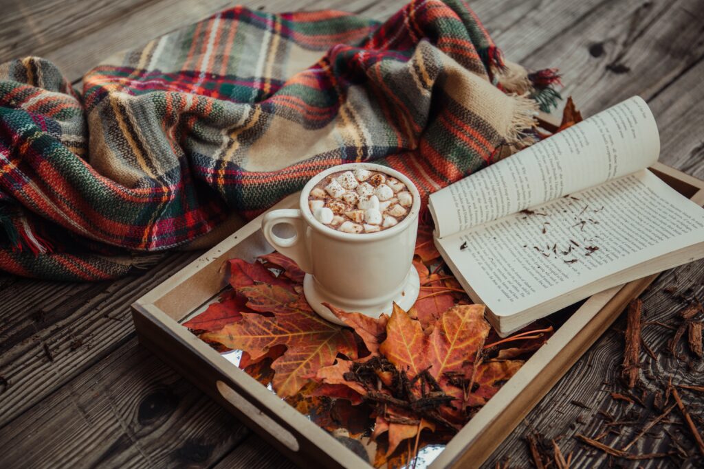 warm drink with marshmellows sitting on a tray of leaves