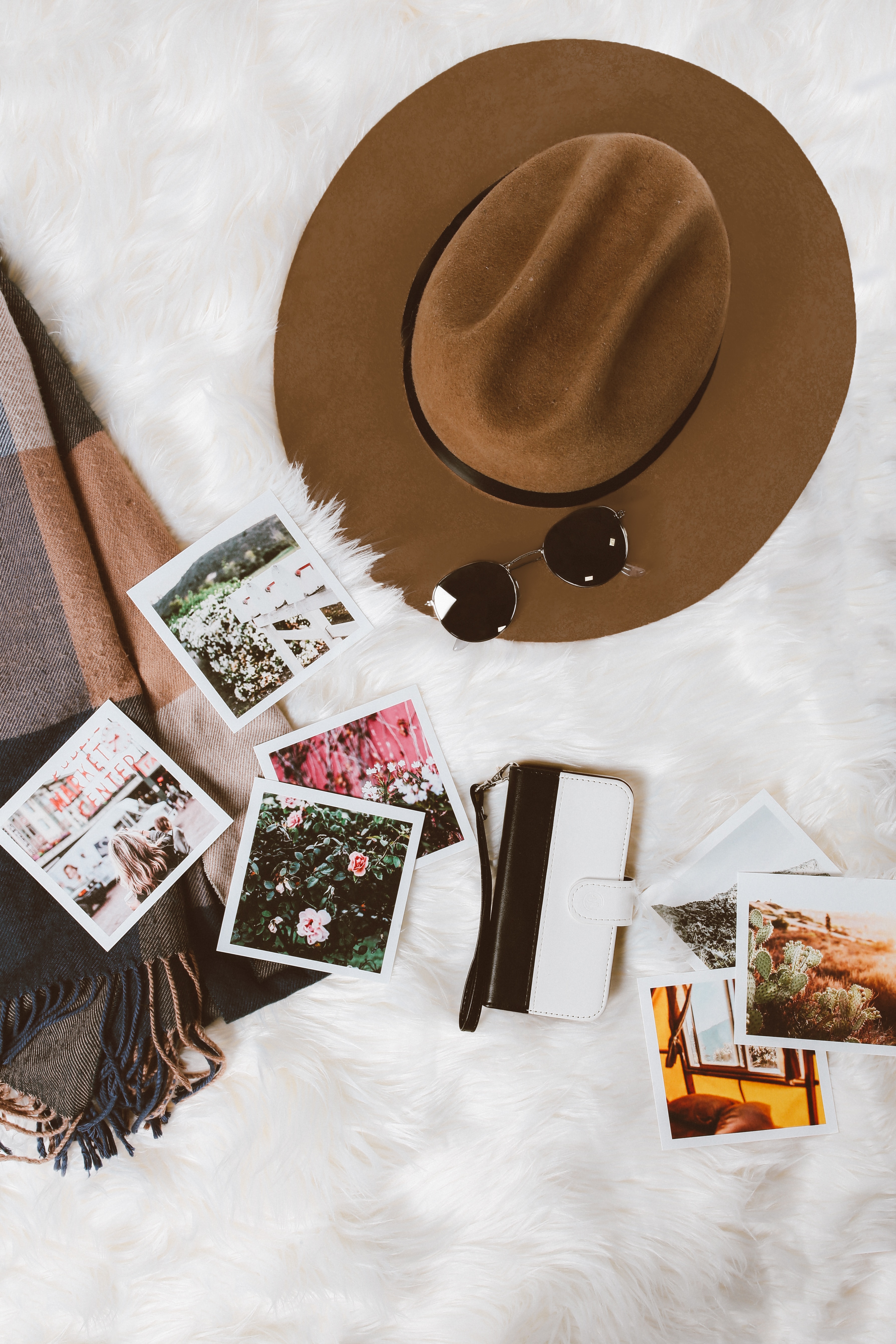 images laid out on a bed and a travel hat. The images are of fall travel destinations