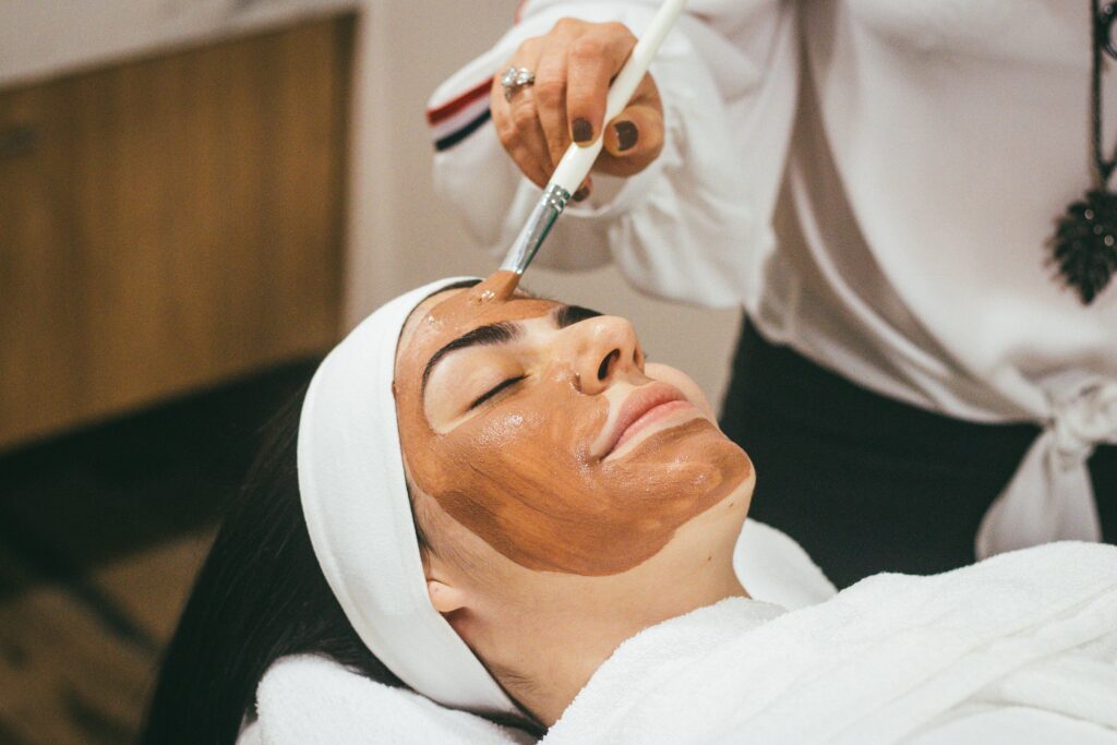 woman getting a facial. A mud mask is being applied using a brush. This is helping with burn out through self-care activities