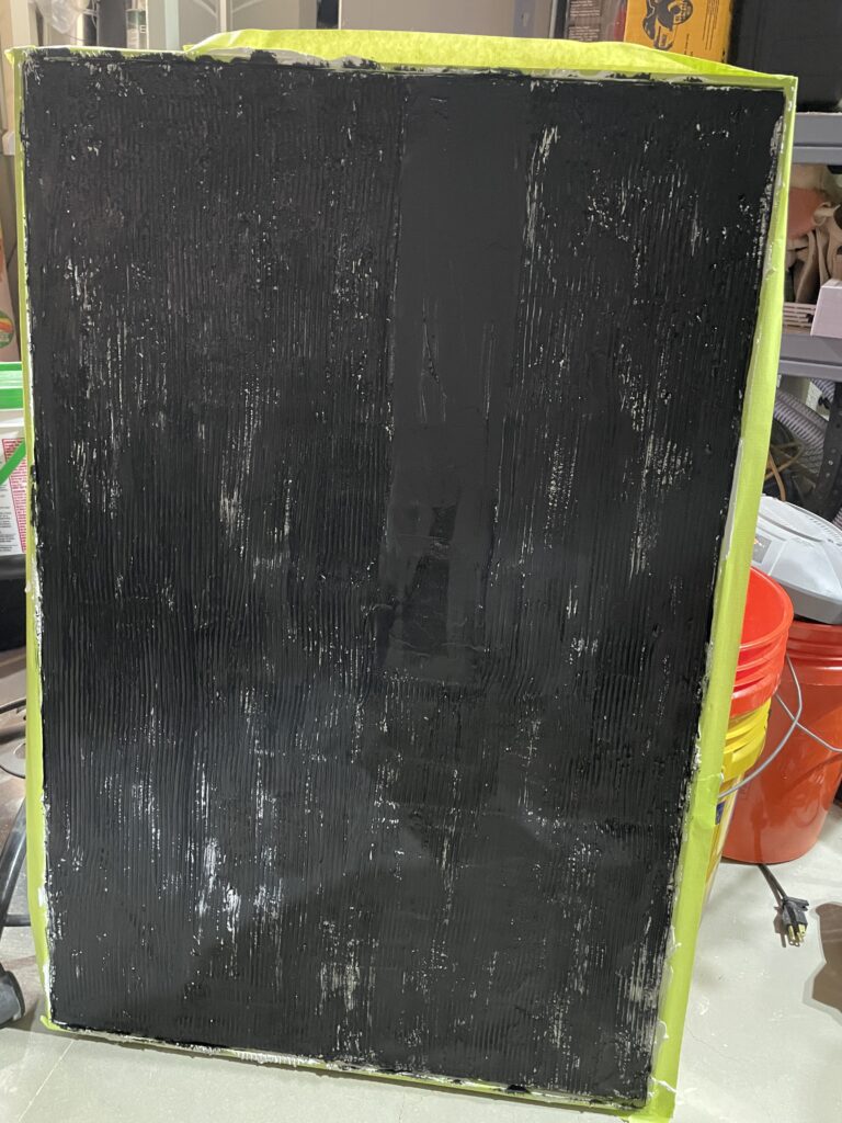 second layer of black paint on plaster artwork.