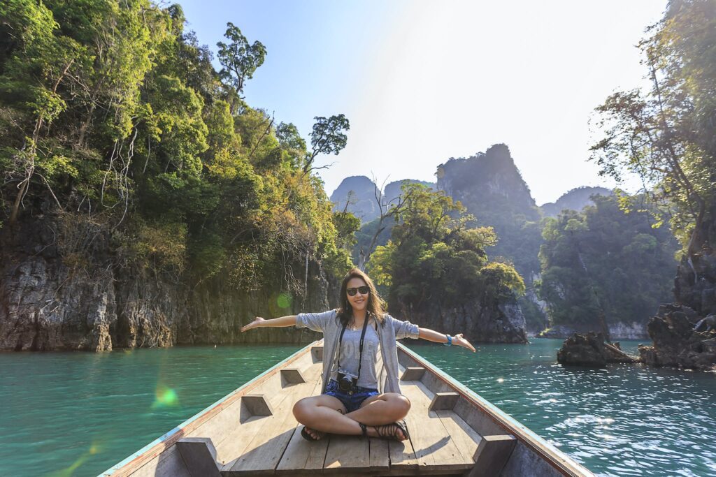 Photo of Woman Sitting on Boat Spreading Her Arms. Traveling is one way to spend your summer vacation